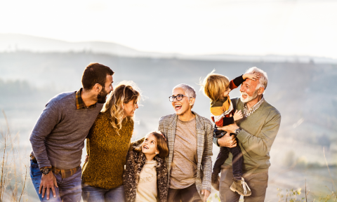 A happy extended family laughs together in the outdoors.